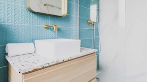 Un baño con lavamanos blanco, espejo y ducha.