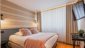 Un dormitorio moderno con cama, televisión y una pequeña mesa con una planta.