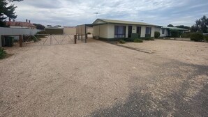 Une maison mobile de plain-pied avec une allée en gravier et une zone délimitée par une clôture.