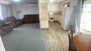 Un espace de vie compact comprenant un canapé, une kitchenette et un coin repas.