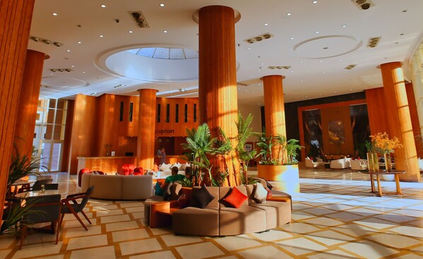 A spacious lobby with high wooden columns, comfortable seating areas, and a reception desk. - Eagles Downtown Zahabia Aqua Park (Hurghada)