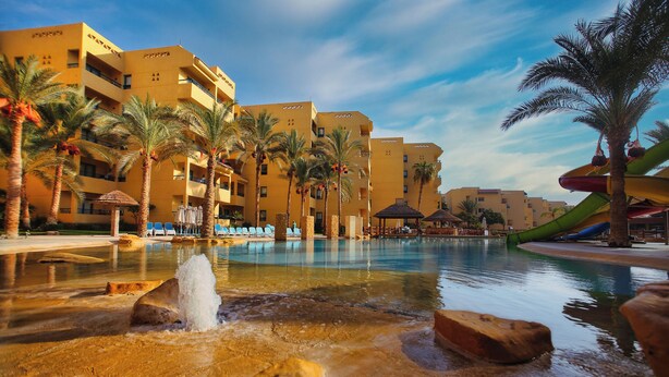 A hotel with a pool area, palm trees, and a water feature. - Eagles Downtown Zahabia Aqua Park (Hurghada)