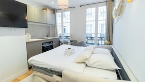 A modern hotel room with a bed, bedside table, and a view of the city through large windows. - Cosy and New Studio Center of Paris (Paris)