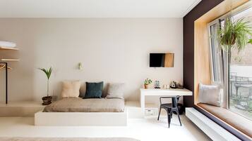 Quarto moderno com cama, escrivaninha e um assento junto à janela.