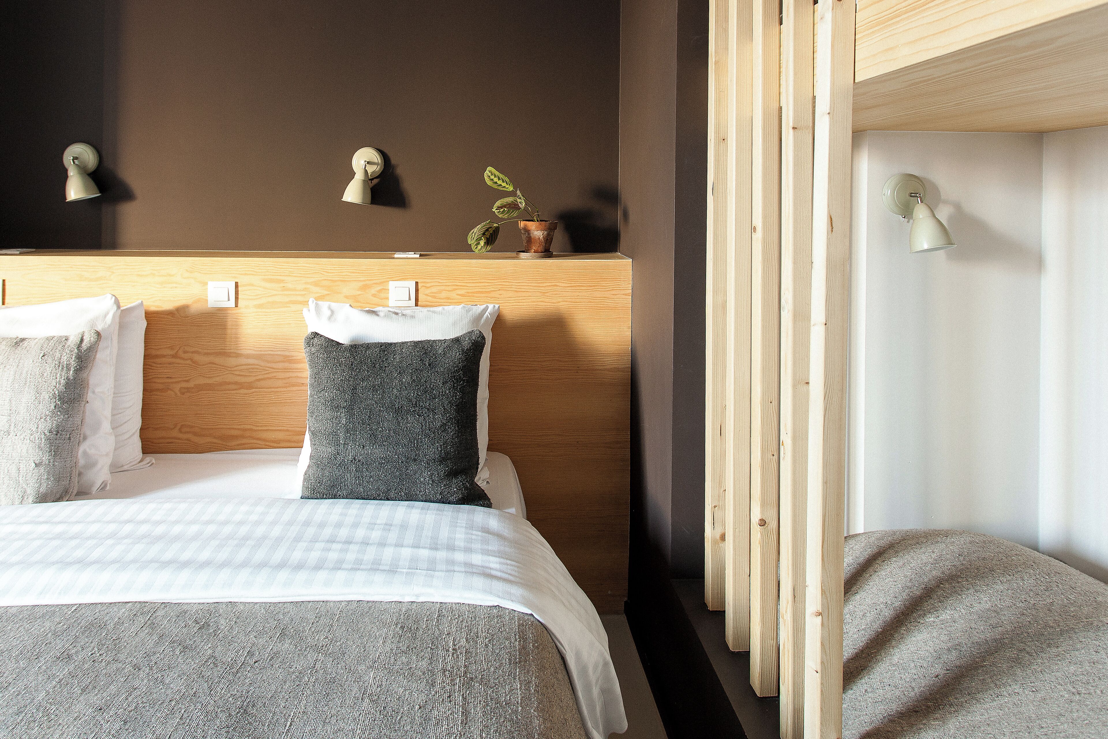 A neatly made bed with a checkered bedspread, a grey pillow, and a white pillow.