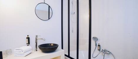 Une salle de bain moderne avec un lavabo blanc, un WC noir et une douche à parois de verre.