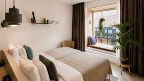Ein modernes Schlafzimmer mit einem großen Bett, einer hängenden Leuchte, einer Sitzbank an einem Fenster mit Blick und einer Topfpflanze.