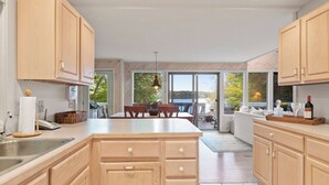 Una cocina moderna con armarios de madera, una isla central y una zona de comedor con vistas al exterior.