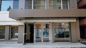 Ένα σύγχρονο κτίριο με μια γυάλινη είσοδο, ένα μπαλκόνι και ένα αυτοκίνητο σταθμευμένο έξω.