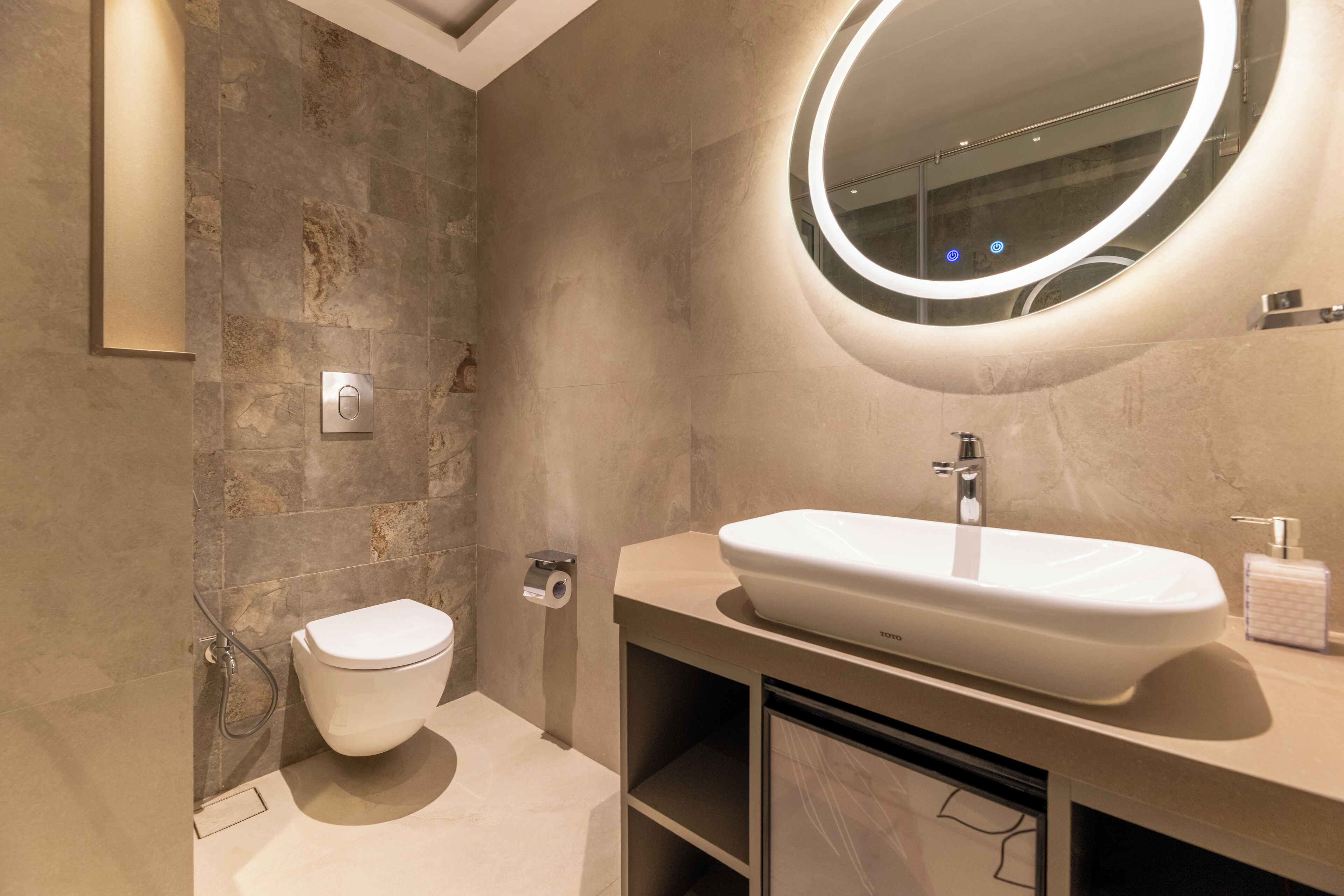 A modern bathroom with a white sink, a round mirror, and a toilet.