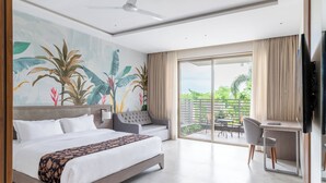 Habitación de hotel con una cama grande, un escritorio y un balcón con vistas a zonas verdes.