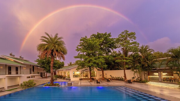 Una piscina con un arcoíris, palmeras y edificios con terrazas.