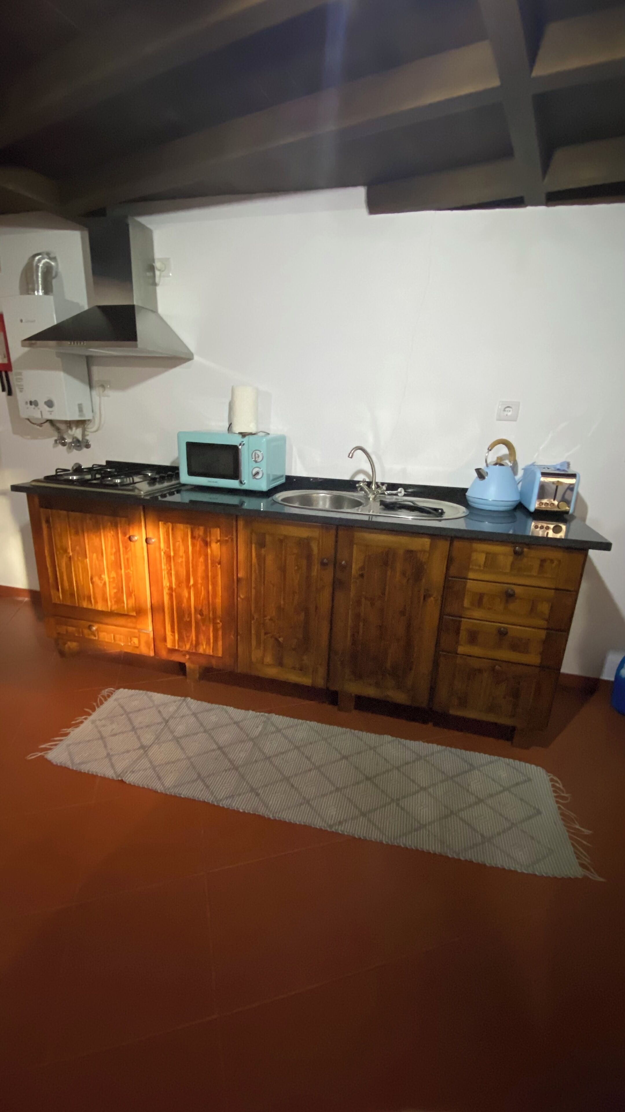 Una cocina con armarios de madera, cocina a gas, microondas, hervidor y tostadora.