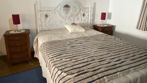 Ein Schlafzimmer mit einem großen Bett, einem hölzernen Nachttisch, einem weißen Kopfteil und einer roten Lampe auf jeder Seite.