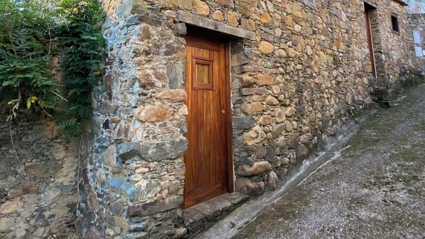 Ein Steinhaus mit einer Holztür und einem kleinen Fenster.