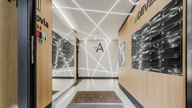 A modern hallway with lockers, a wooden wall, and a geometric light design.