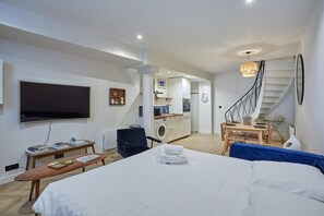 Ein modernes Hotelzimmer mit einem großen Bett, einem Fernseher, einem Schreibtisch und einer Küchenzeile.