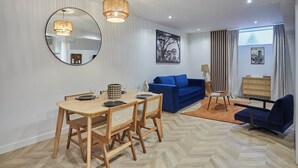 A modern living room with a dining area, a blue sofa, a lamp, and a large mirror. - Charming & Modern Duplex Apartment Center of Paris (Paris)
