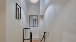 A narrow hallway with a staircase, white walls, and two framed artworks. - Charming & Modern Duplex Apartment Center of Paris (Paris)
