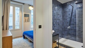 A bedroom with a bed, a dresser, and a window with curtains. - Charming & Modern Duplex Apartment Center of Paris (Paris)