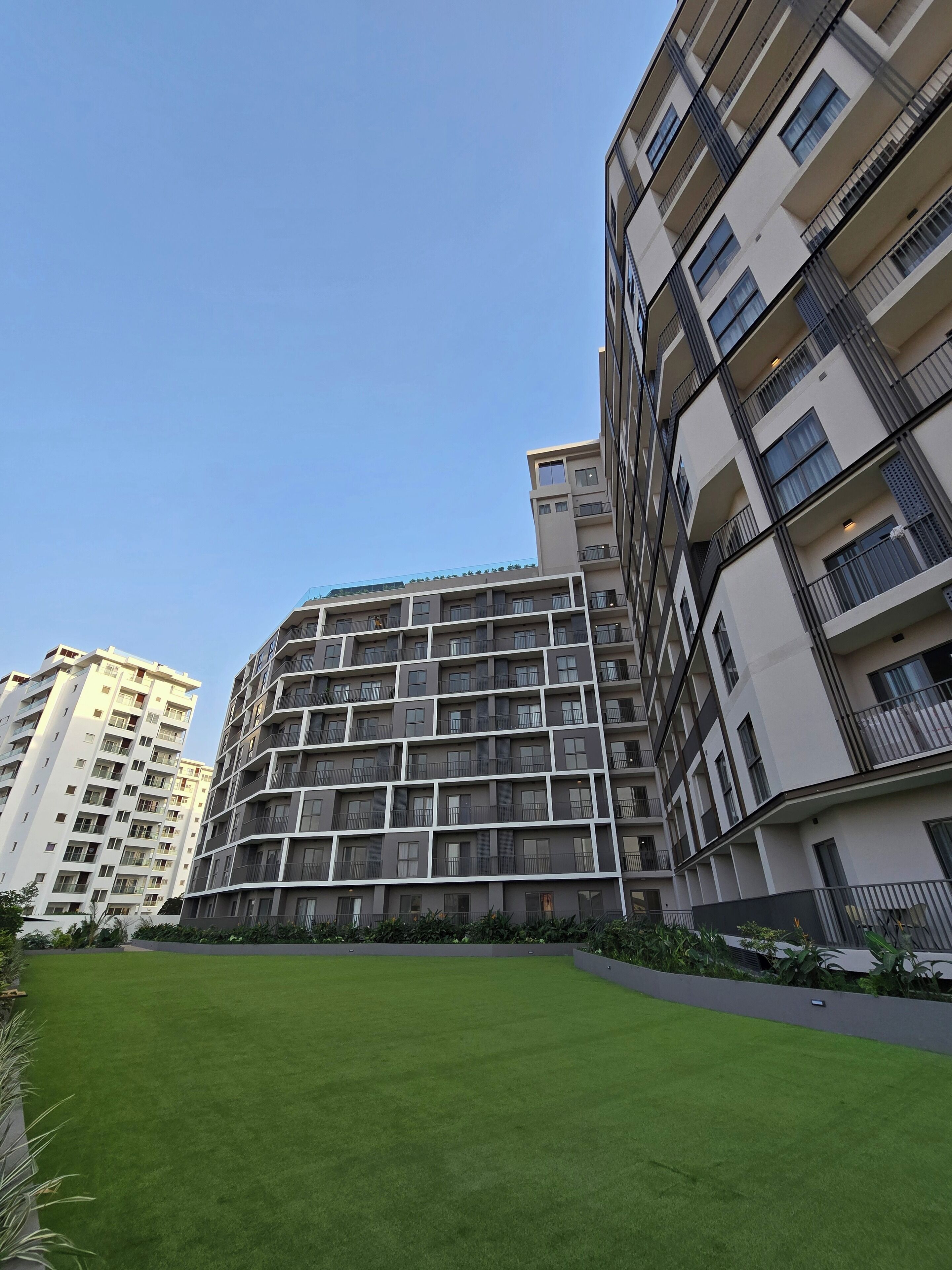 A multi-story residential building with balconies and a well-maintained lawn in front.