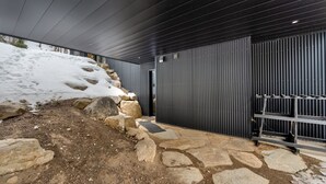 A modern building with a stone and metal exterior, a metal door, and a stone pathway leading to a door.