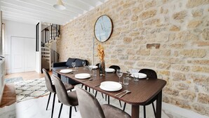 A dining area with a stone wall, a clock, and a staircase. - Welcoming Apartment - 2br/8p - Bonne-nouvelle (Paris)
