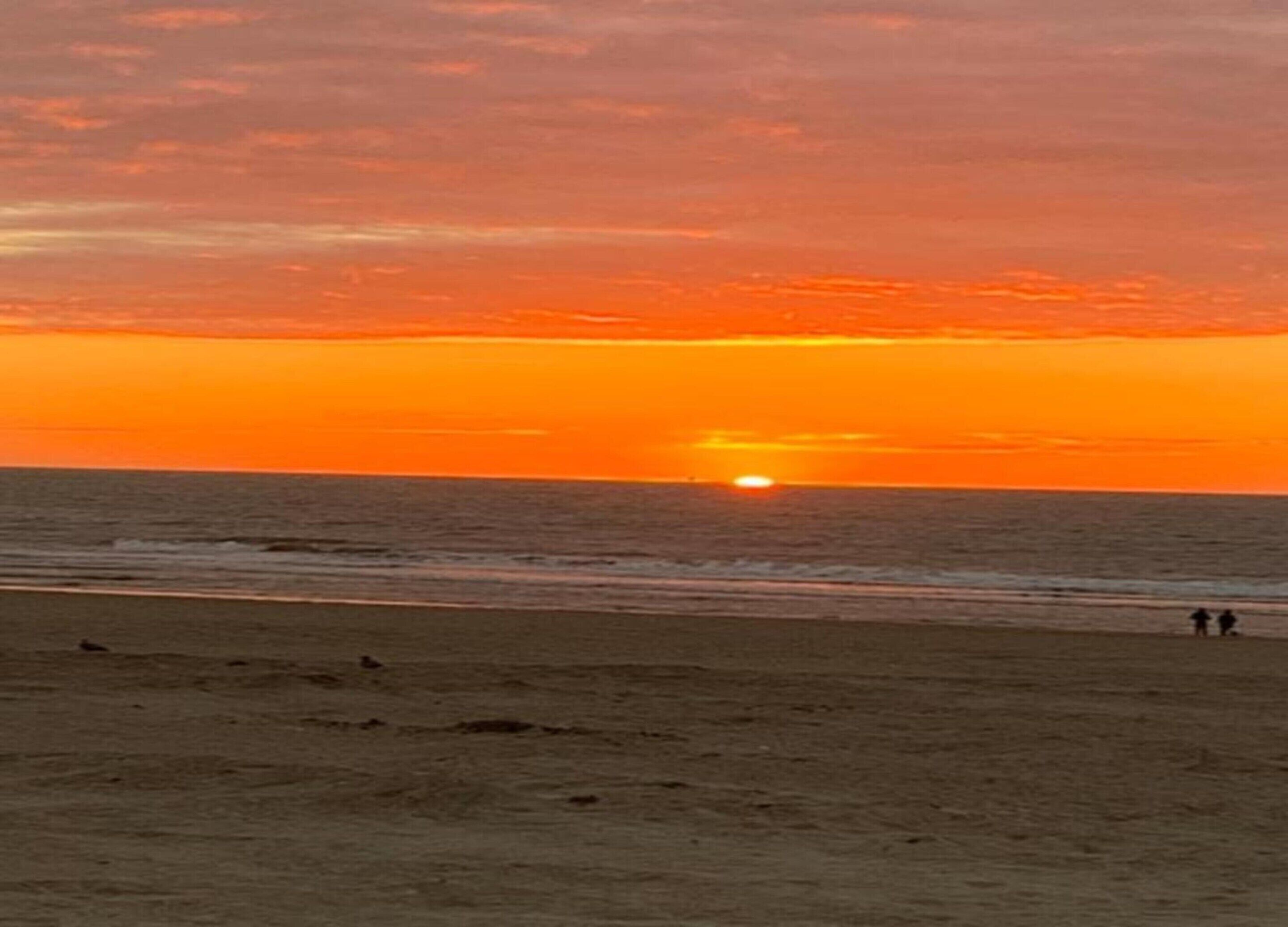 Scena di spiaggia con un tramonto sull'oceano.
