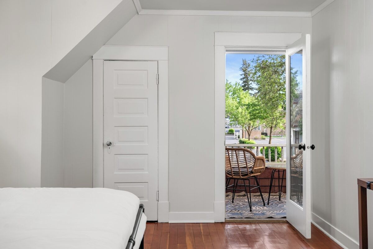 A bedroom with a white door leading to an outdoor patio with a table and chairs.