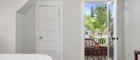 A bedroom with a white door leading to an outdoor patio with a table and chairs.