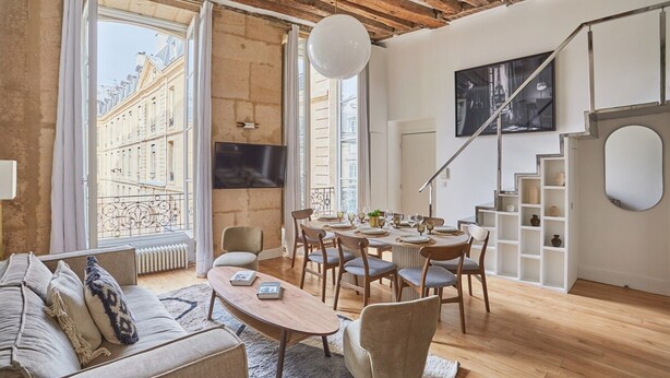 Ein modernes Wohnzimmer mit Holzbalkendecke, einem Essbereich und einer Treppe.
