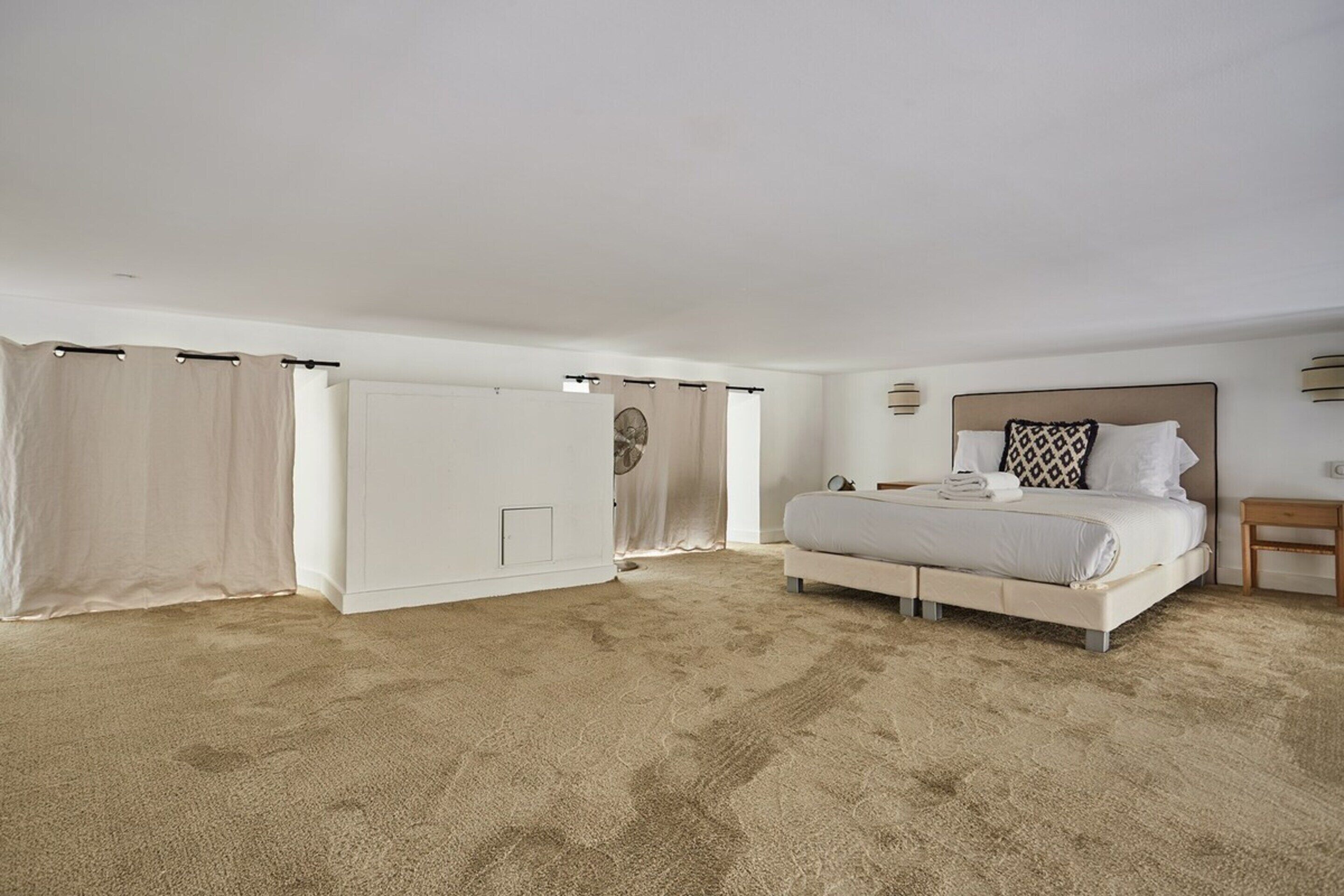 A spacious bedroom with a large bed, a walk-in closet, and a ceiling fan.