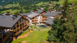 A cluster of wooden chalet-style buildings with multiple balconies, a swimming pool, and a well-maintained lawn. - Charming Apt With View 2bd/6p -residence in Mega\"ve (Megeve)