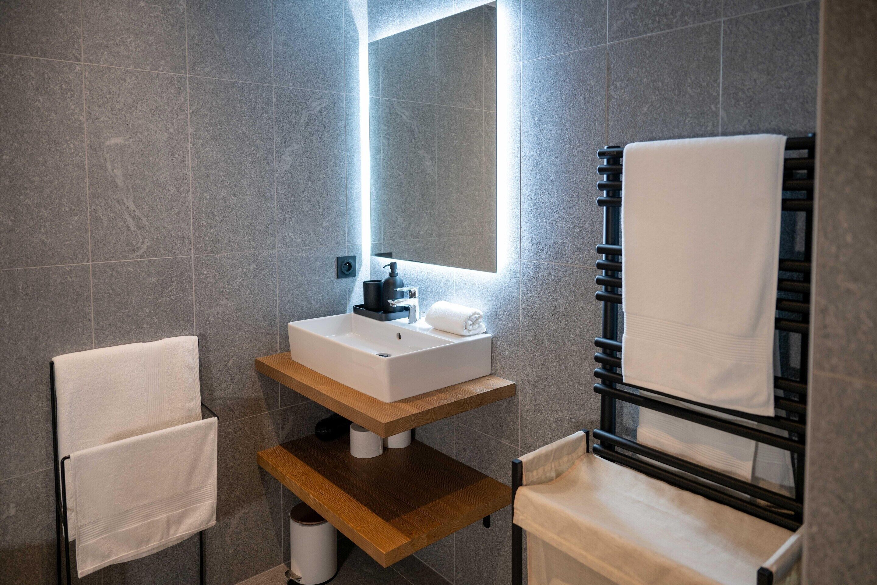 A modern bathroom with a built-in sink, a mirror, and a towel rack.
