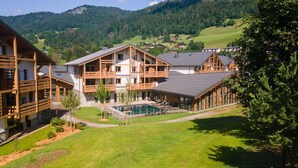 A modern chalet-style building with a pool, surrounded by lush greenery and mountains in the background. - Charming Apt With View 2bd/6p -residence in Mega\"ve (Megeve)