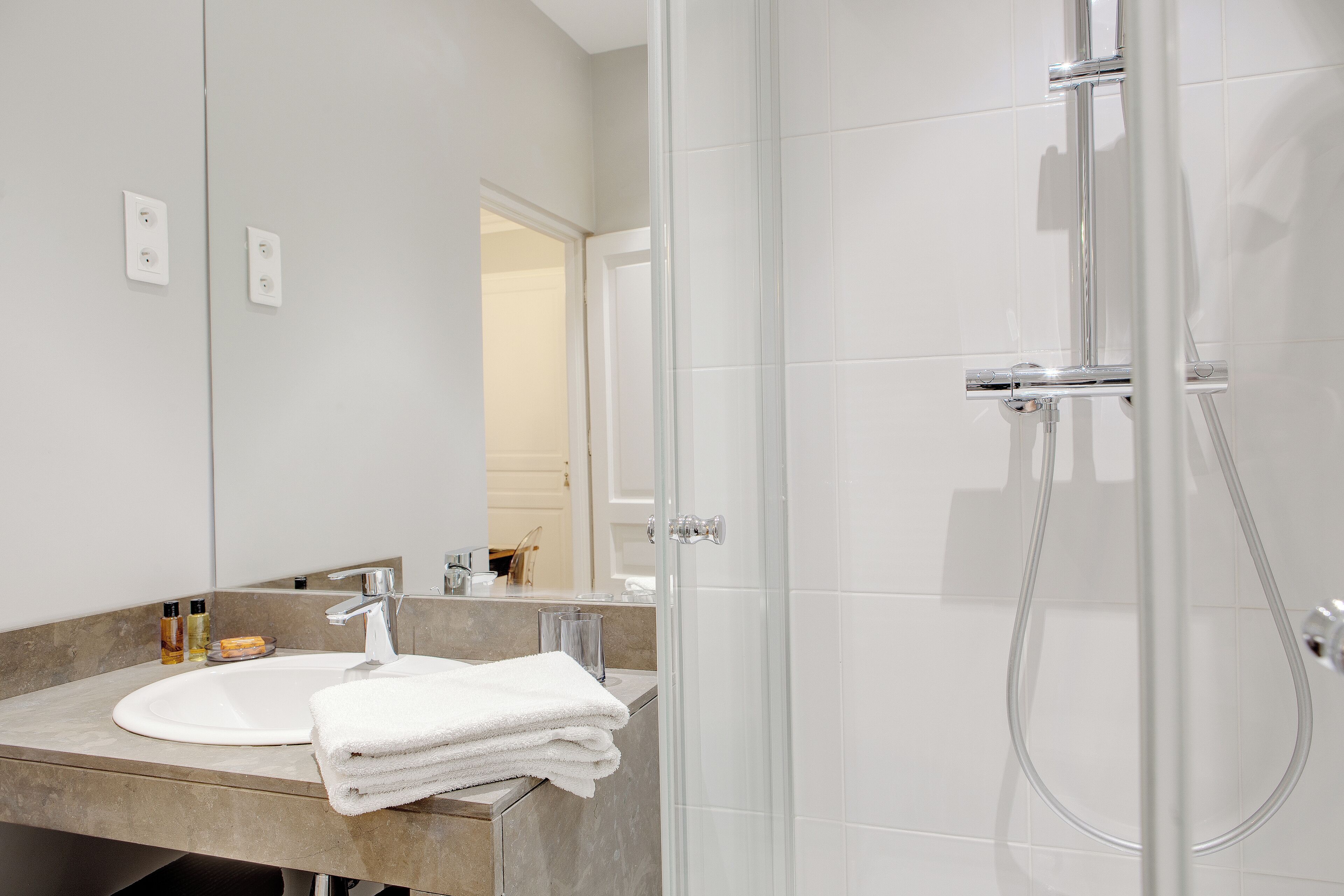 A modern bathroom with a sink, mirror, and shower.