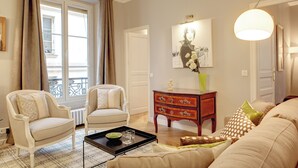 A living room with two armchairs, a coffee table, a side table with a vase, and a painting on the wall.