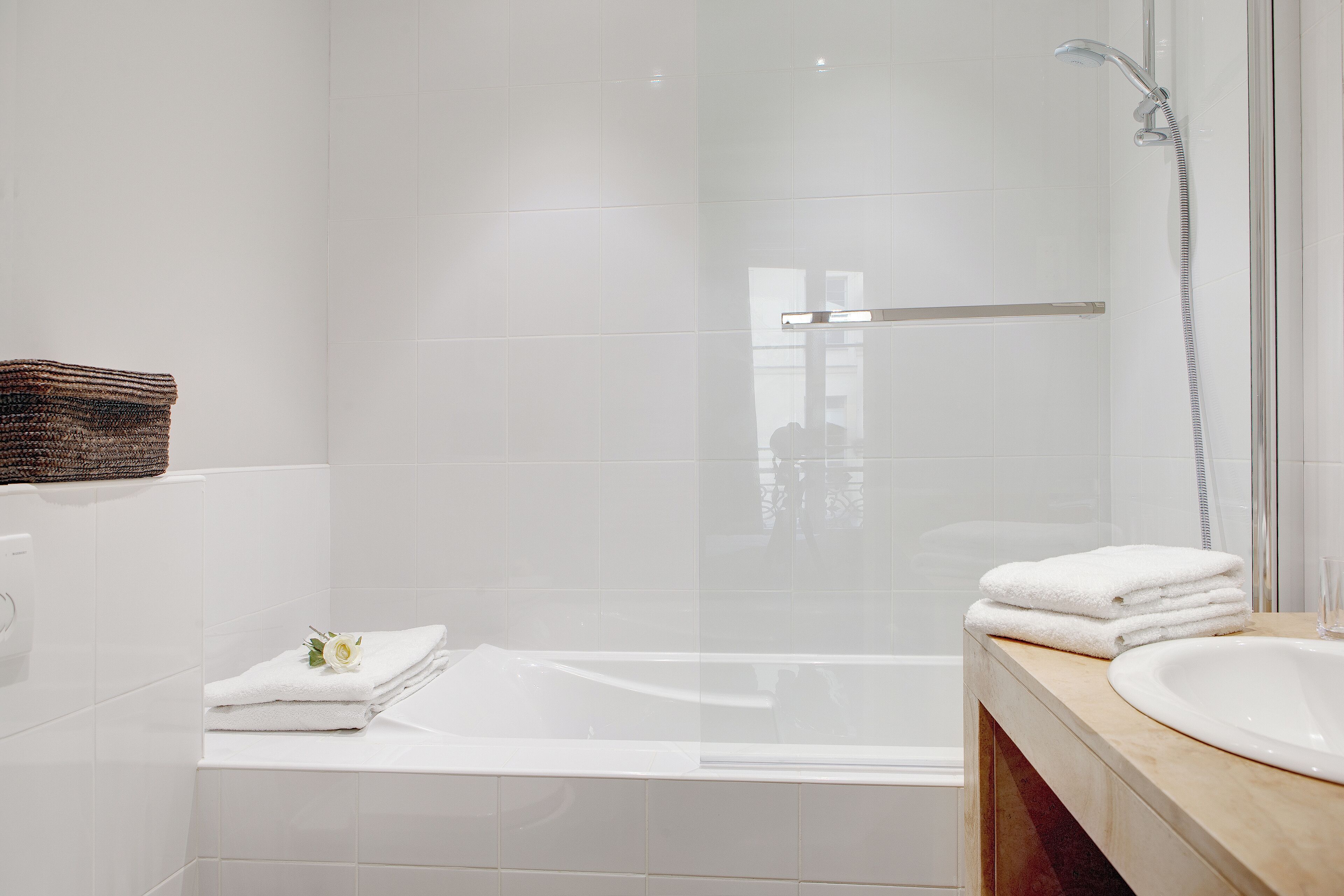 Une salle de bain moderne avec une douche à parois de verre, une baignoire blanche et un lavabo sur lequel est posée une serviette.