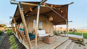 Eine Holzterrasse mit Markise, Korbmöbeln und einer Hängeleuchte.