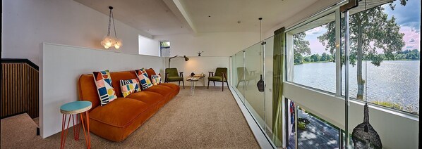 A modern living room with a sofa, chairs, and a view of a lake.