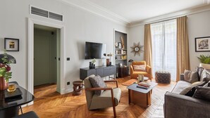 A modern living room with a flat-screen TV, a sofa, a coffee table, and a bookshelf. - Magnificent new Apartment Notre Dame de Paris (Paris)