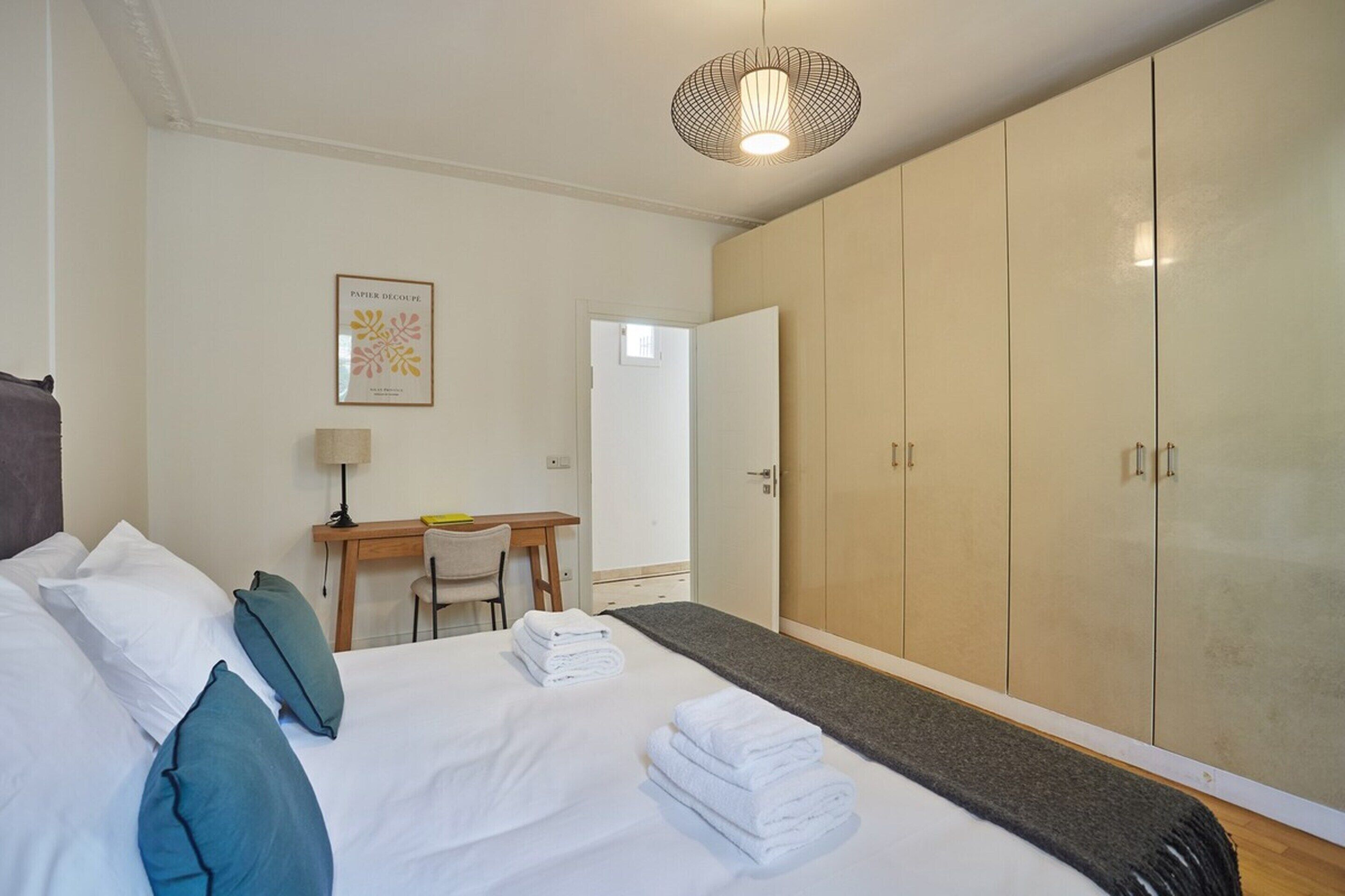 Een hotelkamer met een bed, een bureau, een kledingkast en een deur.