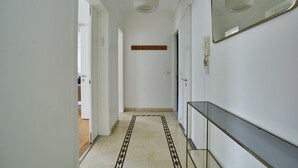 Un couloir avec un sol à motifs, un miroir et une étagère.