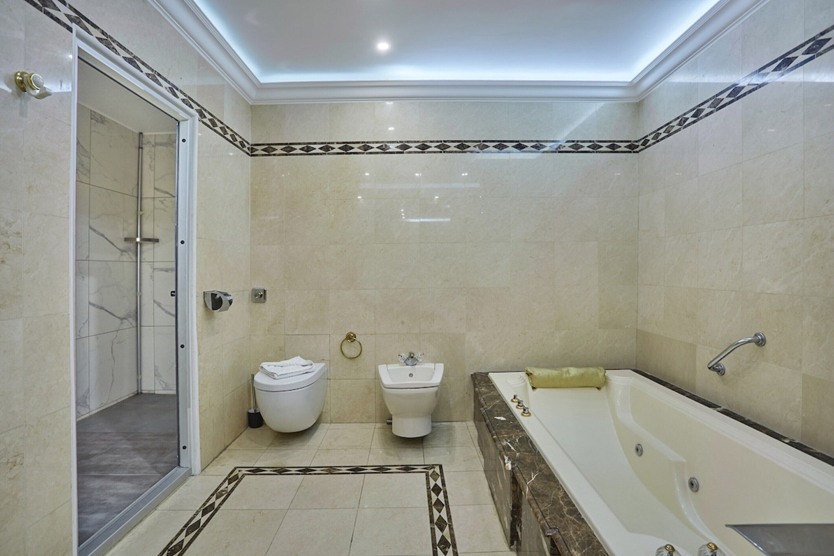 A bathroom with a shower, toilet, bidet, and bathtub.