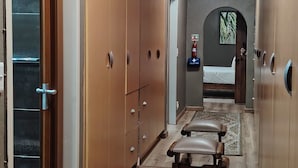 Un pasillo con armarios de madera, un banco y una alfombra estampada.