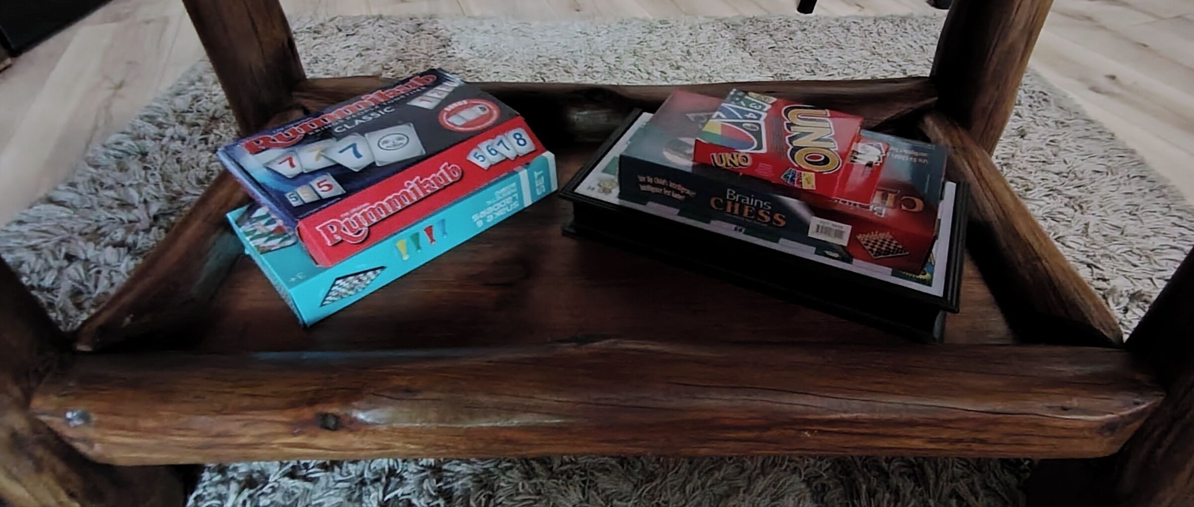Een houten stoel met twee gezelschapsspellen, Rummikub en UNO, op een vloerbedekking.