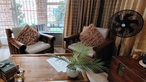 Una sala de estar acogedora con dos sillones de cuero, una mesa de centro de madera, un ventilador y una planta en maceta.