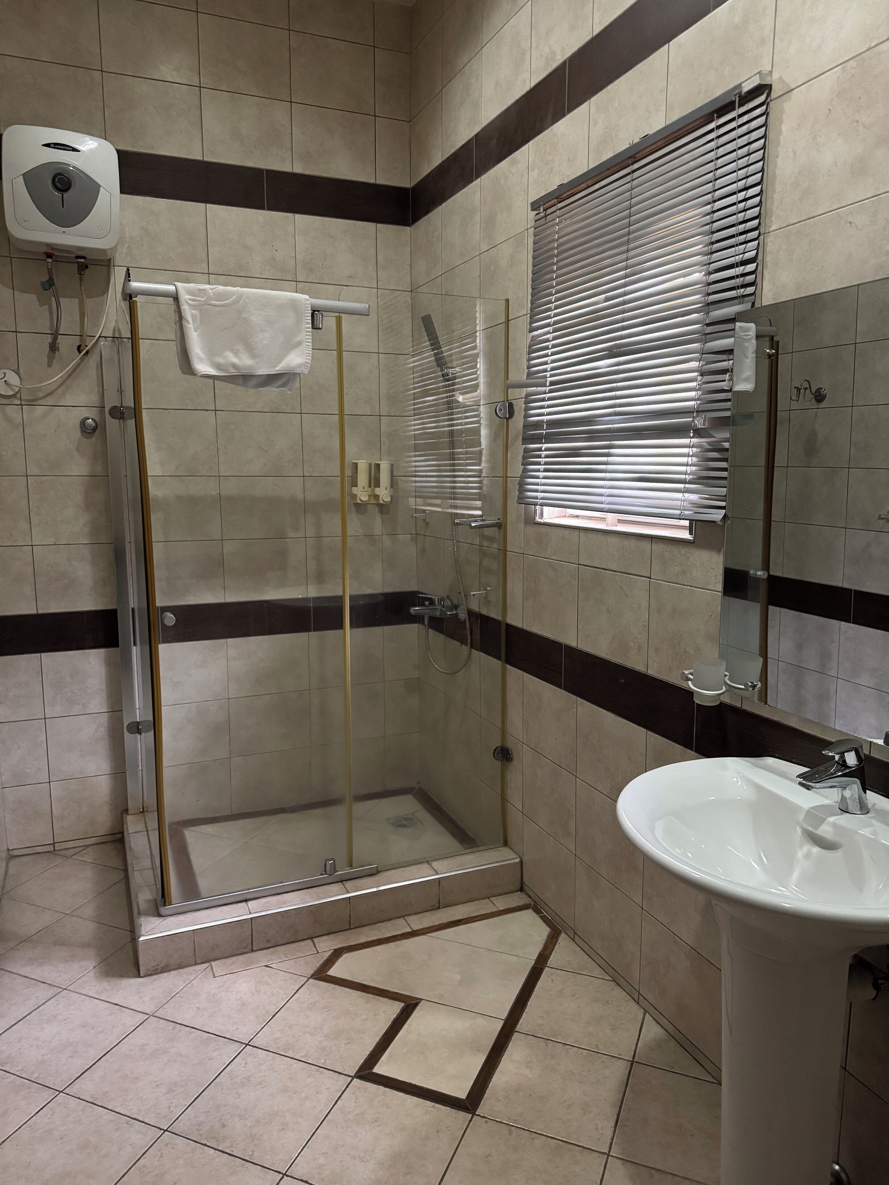 A bathroom with a glass-enclosed shower, a sink, and a hand dryer.