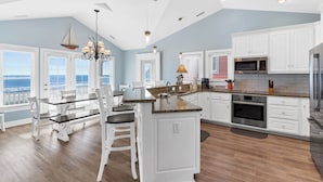 Una cocina amplia con armarios blancos, una isla central y vistas al exterior.