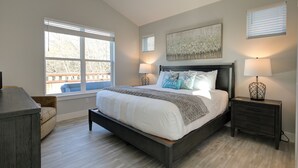 A bedroom with a large bed, two bedside tables with lamps, a ceiling fan, and a window with blinds. - Welcome to your ultimate getaway, Burl by the Bay! (Ocean Shores)